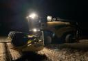 Photo of a farmer harvesting their crop into the night during a brief dry spell.