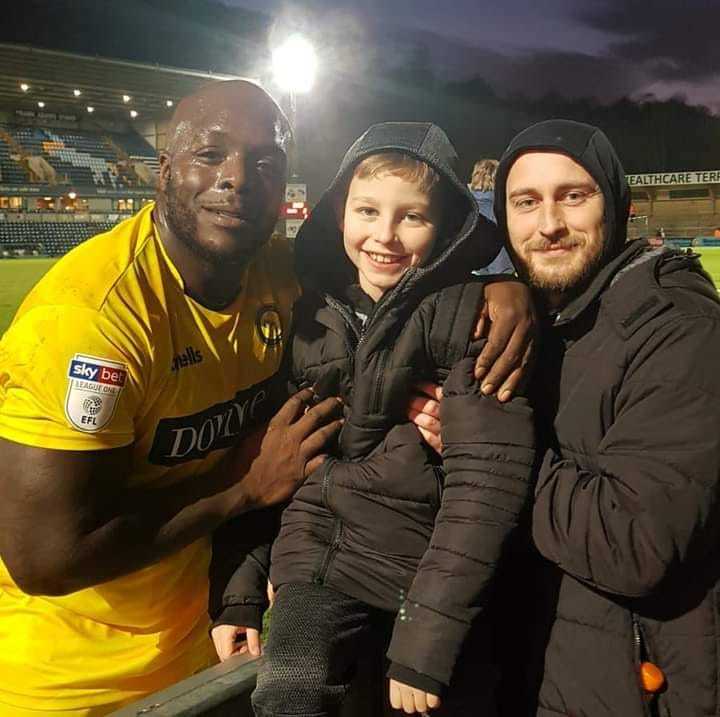 Two fans pose with Bayo after the 2-1 win aganst Rochdale at Adams Park in January 2020 (Luke Rollie Hagley)
