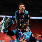 Paul Smyth with Adebayo Akinfenwa after the League One play-off win against Oxford United in July 2020, which earned the Chairboys promoted to the Championship (PA)