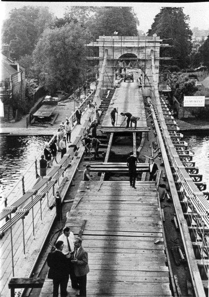 Looking N, an elevated view of work to repair the bridge; the carriageway is being renewed and the N suspension tower rebuilt. Marlow. c 1965.