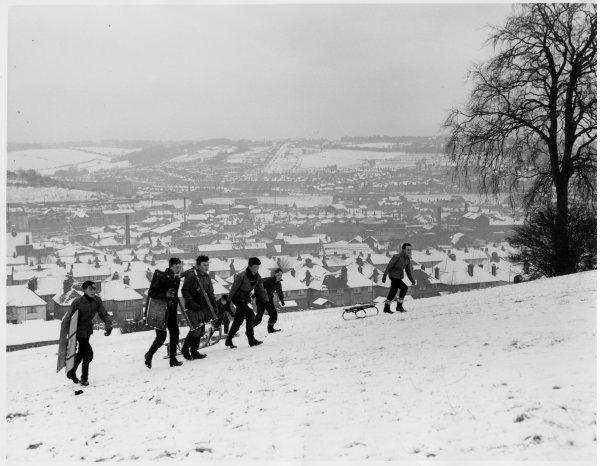 View over the western side of the town after a fall of snow, with boys walking up the hill with their toboggans, Carver Hill, High Wycombe. January 1960