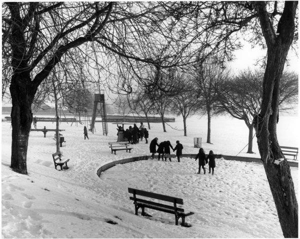 View of children playing in the playground after a moderate fall of snow, The Rye, High Wycombe. Circa 1970