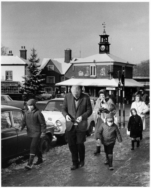 View of pedestrians in the street, with the Market House behind which is decorated for Christmas, Market Place, Princes Risborough. December 1967