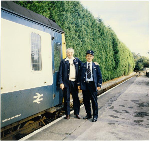 A view of a driver and guard standing on the platform beside the rear carriage of a Maidenhead, Bourne End, Marlow train, March 1981.