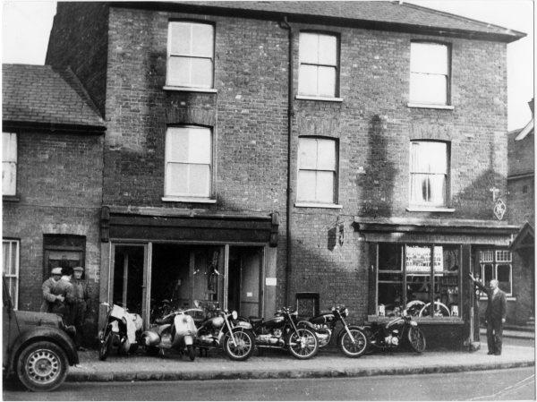 Looking north east, a view of Goddard's motorcycle shop, with motorcycles and scooters on display outside. Corner of Desborough Road/Mendy Street, High Wycombe. 1950's