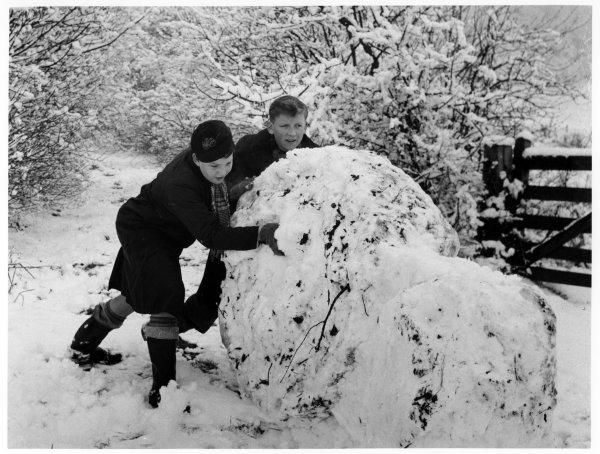 Two boys playing in the snow, rolling a giant snowball, West Wycombe Estate, West Wycombe. February 1953