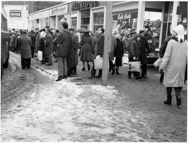 Looking E, a view of the southern side street, which is busy with shoppers and people waiting for buses, after a fall of snow. Oxford St, High Wycombe. c 1968