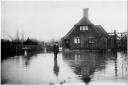 A man standing up to his knees in flood water in the garden of a house, Marlow. 1947