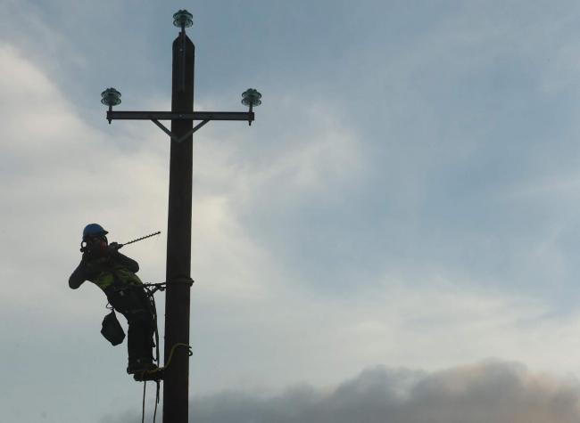 A man fixing an overhead powerline. Credit: PA