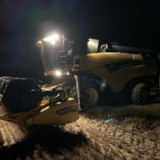 Photo of a farmer harvesting their crop into the night during a brief dry spell.