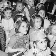 Children of employees of Hoover Ltd, including Diana and Mary Farmbrough (centre left Diana, centre right Mary), watch a film show during their annual party held in the works canteen, Coronation Rd, High Wycombe, March 1952.